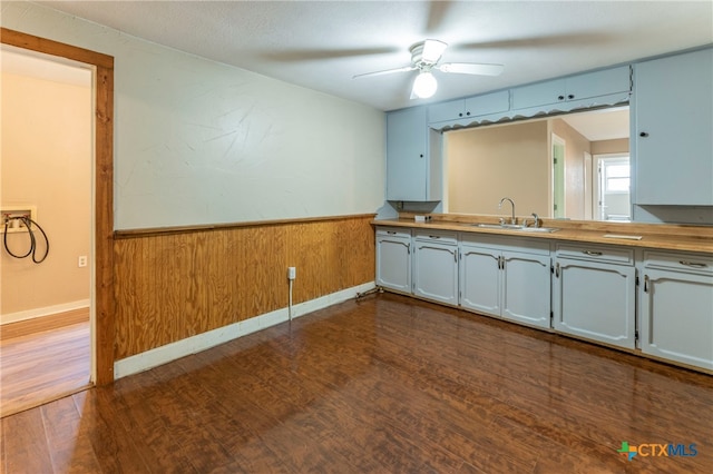 kitchen featuring wood walls, wooden counters, sink, ceiling fan, and dark hardwood / wood-style flooring