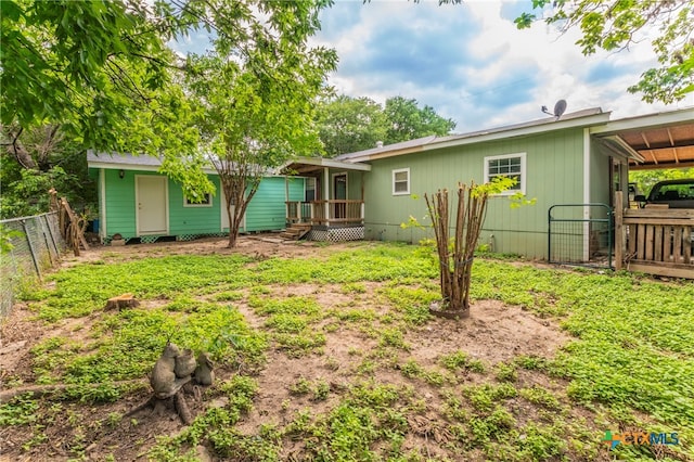 rear view of property with a wooden deck and a carport