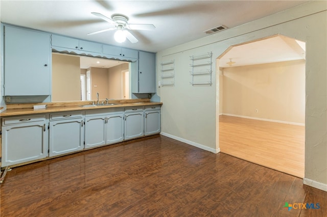 kitchen with butcher block counters, ceiling fan, dark wood-type flooring, and sink