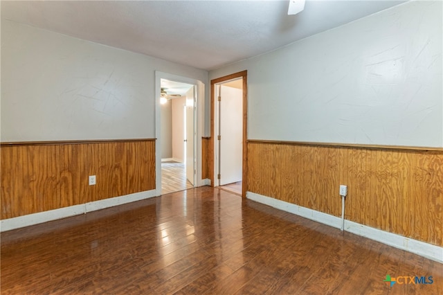 spare room with hardwood / wood-style flooring, ceiling fan, and wood walls