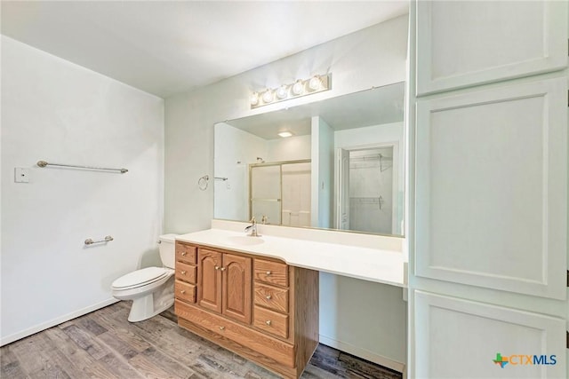 bathroom with vanity, wood-type flooring, a shower with door, and toilet