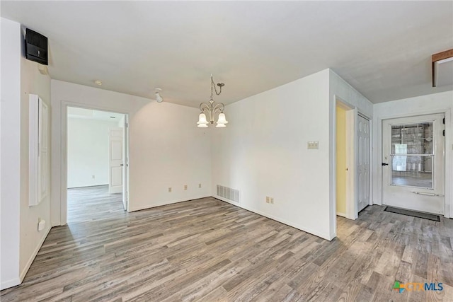 spare room featuring an inviting chandelier and hardwood / wood-style floors