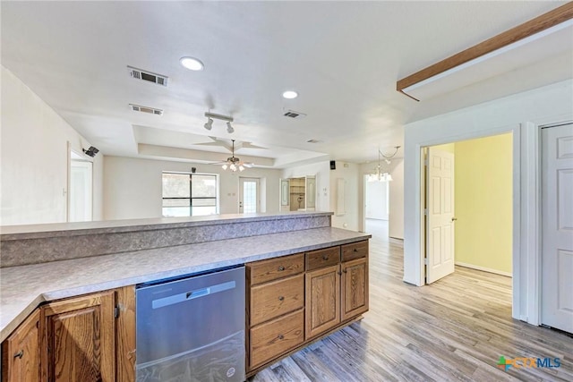 kitchen featuring stainless steel dishwasher, a raised ceiling, ceiling fan, and light wood-type flooring