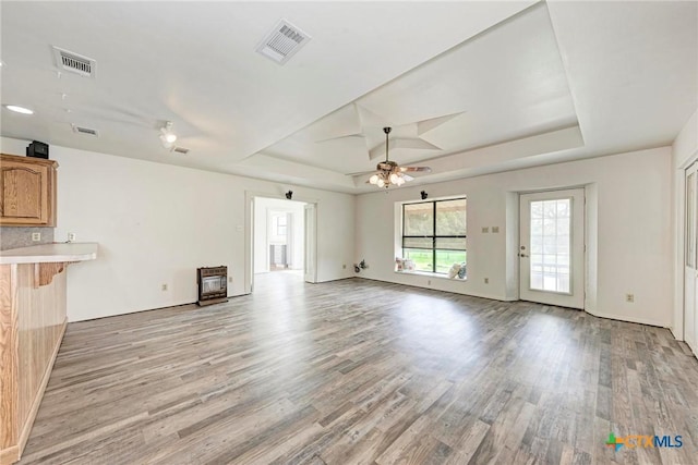 unfurnished living room featuring a tray ceiling, light hardwood / wood-style floors, and ceiling fan