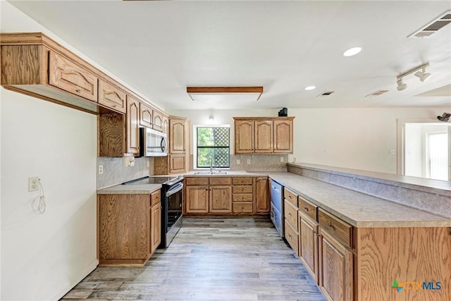 kitchen with stainless steel appliances, backsplash, light wood-type flooring, and kitchen peninsula