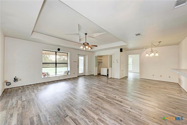 unfurnished living room with plenty of natural light, a raised ceiling, and light wood-type flooring