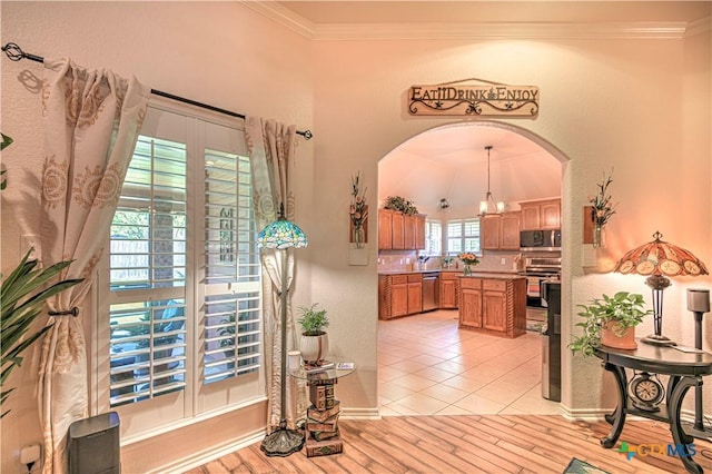 1521 Shadow Canyon Dr, Temple, TX 76502 - kitchen with appliances with stainless steel finishes, arched walkways, crown molding, brown cabinets, and a center island