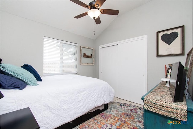 bedroom featuring lofted ceiling, light tile patterned flooring, ceiling fan, and a closet