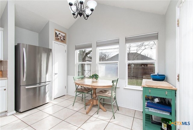 tiled dining space with lofted ceiling and a chandelier