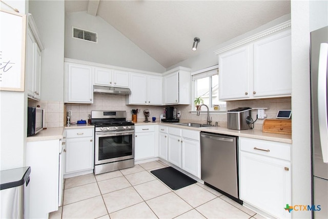 kitchen with appliances with stainless steel finishes, white cabinetry, high vaulted ceiling, and sink