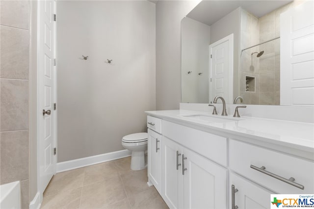 bathroom with vanity, tile patterned flooring, toilet, and tiled shower