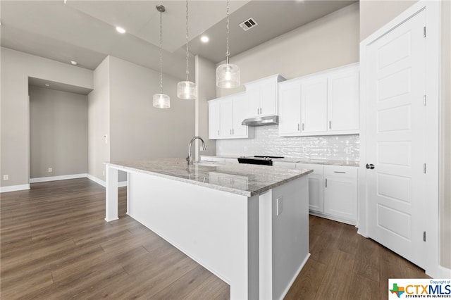 kitchen with an island with sink, hanging light fixtures, white cabinets, and dark wood-type flooring