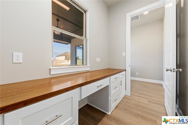 unfurnished office featuring light wood-type flooring and built in desk