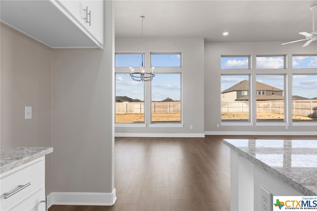 unfurnished living room featuring dark wood-type flooring and ceiling fan with notable chandelier