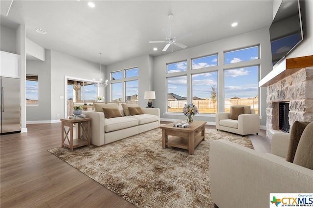 living room with hardwood / wood-style floors, a fireplace, and ceiling fan with notable chandelier