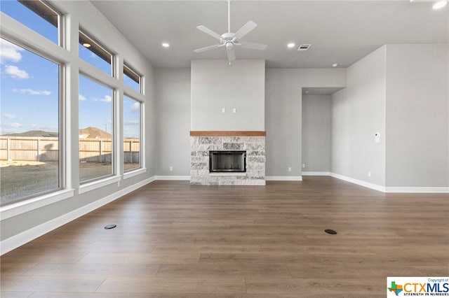 unfurnished living room featuring a fireplace, dark hardwood / wood-style flooring, and ceiling fan