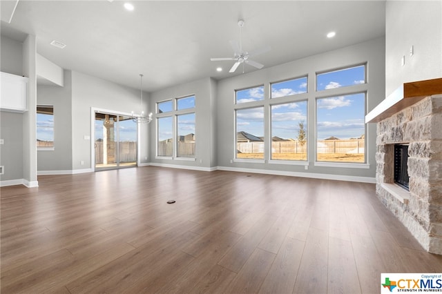 unfurnished living room with a fireplace, dark hardwood / wood-style floors, and ceiling fan with notable chandelier