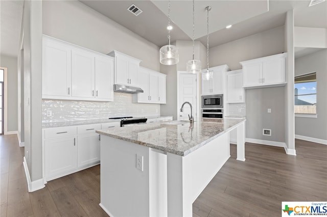 kitchen with a kitchen island with sink, stainless steel appliances, white cabinetry, and pendant lighting