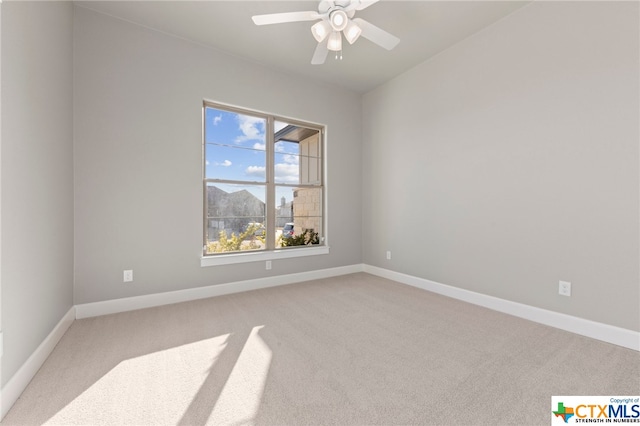 unfurnished room featuring a mountain view, light carpet, and ceiling fan