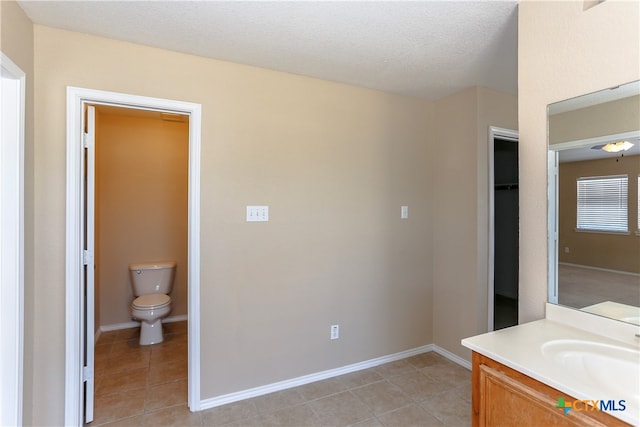 bathroom with tile patterned flooring, vanity, a textured ceiling, and toilet