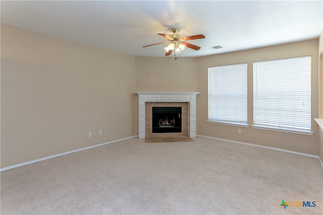 unfurnished living room with a fireplace, light colored carpet, and ceiling fan