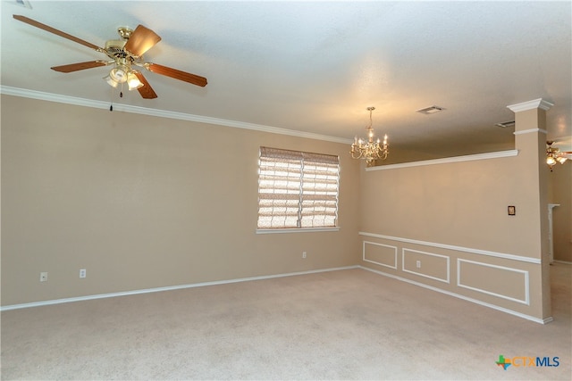 carpeted spare room with ceiling fan with notable chandelier, crown molding, and decorative columns