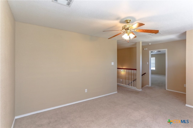 spare room with a textured ceiling, light carpet, and ceiling fan