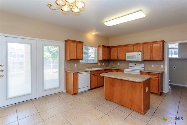 kitchen with light tile patterned flooring, white appliances, a kitchen island, and backsplash