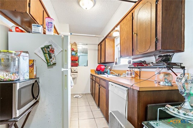 1203 Urbantke Ct Unit A-H, Copperas Cove, TX 76522 - kitchen with white appliances, a textured ceiling, light countertops, light tile patterned flooring, and brown cabinets