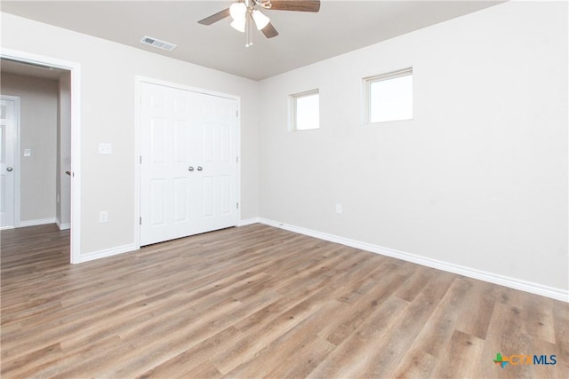 unfurnished bedroom featuring ceiling fan, a closet, and light hardwood / wood-style flooring