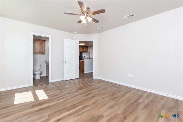 unfurnished bedroom featuring hardwood / wood-style flooring, ceiling fan, stainless steel fridge, and ensuite bathroom