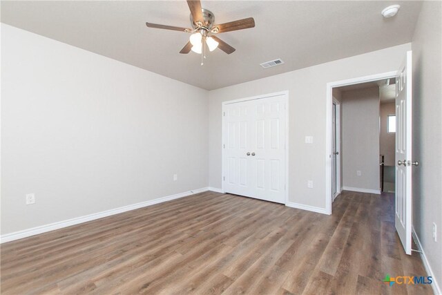 unfurnished bedroom with ceiling fan, a closet, and dark wood-type flooring