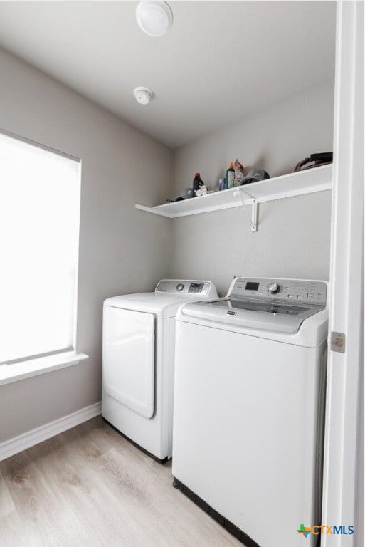 laundry room with washing machine and dryer and light wood-type flooring