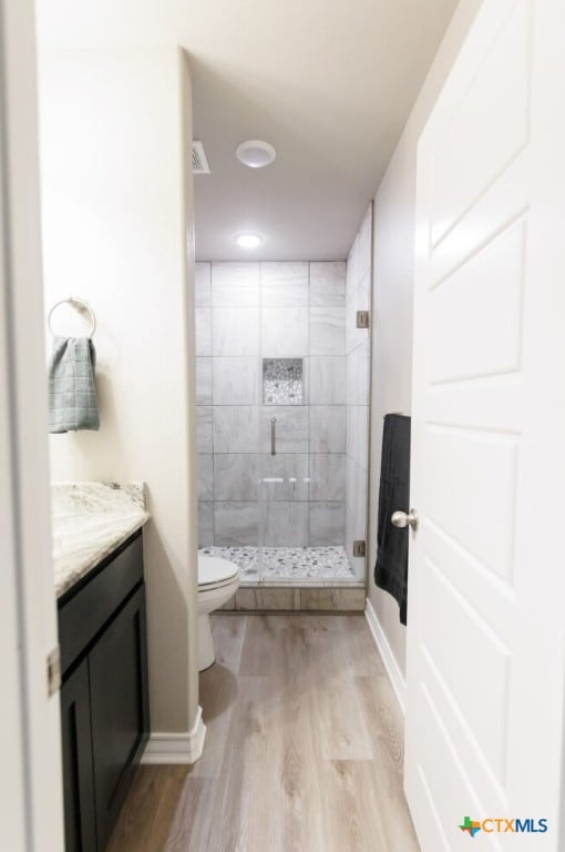 bathroom featuring hardwood / wood-style floors, vanity, toilet, and a shower with shower door