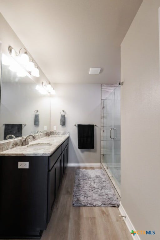 bathroom featuring a shower with door, vanity, and hardwood / wood-style flooring