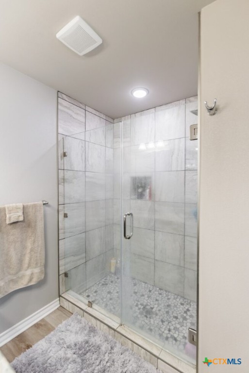 bathroom featuring wood-type flooring and an enclosed shower