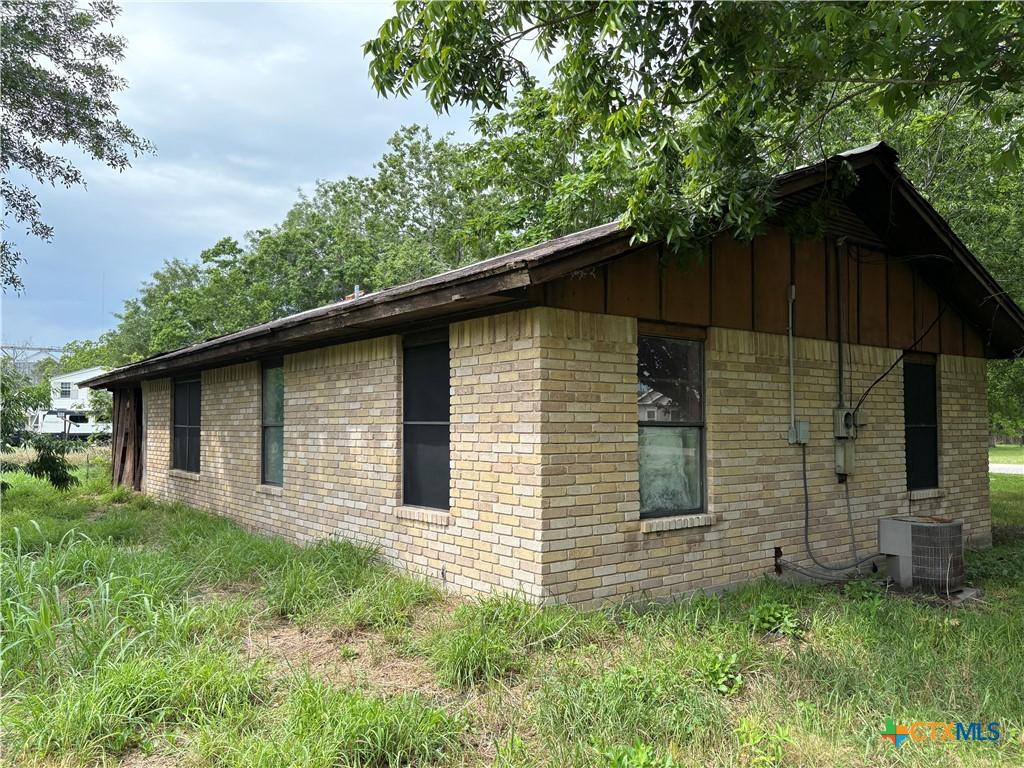 116 S Williams St, Placedo, TX 77977 - view of side of property with cooling unit, brick siding, and board and batten siding