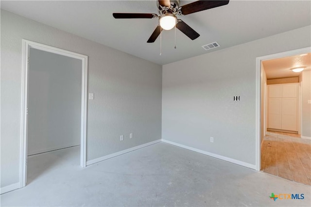 spare room featuring visible vents, concrete floors, baseboards, and ceiling fan