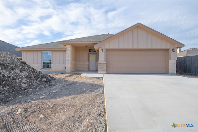 view of front of house featuring a garage, concrete driveway, fence, board and batten siding, and brick siding