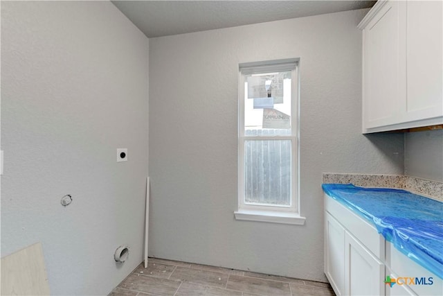 laundry area featuring wood tiled floor, hookup for an electric dryer, and cabinet space