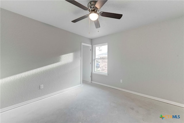 spare room featuring a ceiling fan, baseboards, and concrete flooring