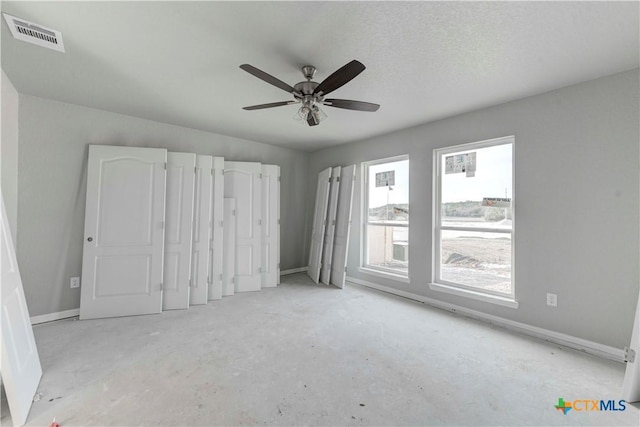 unfurnished bedroom with baseboards, unfinished concrete floors, visible vents, and ceiling fan