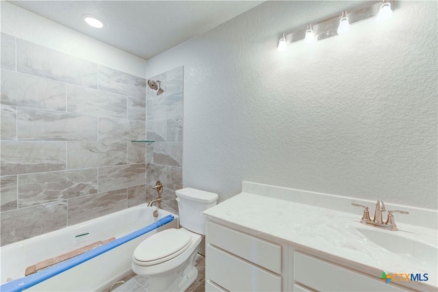 bathroom featuring a textured wall, shower / bathing tub combination, vanity, and toilet