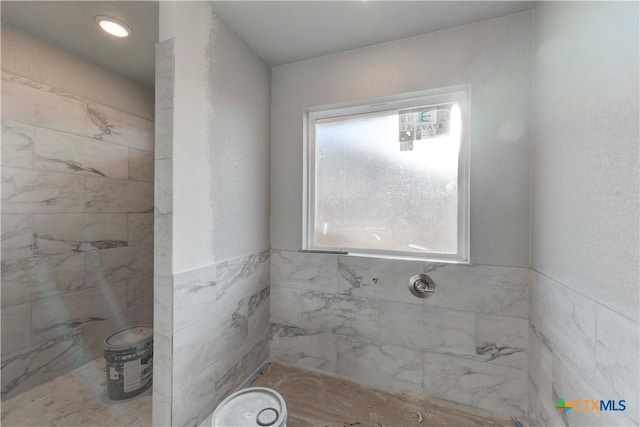 bathroom with a tile shower and a wealth of natural light