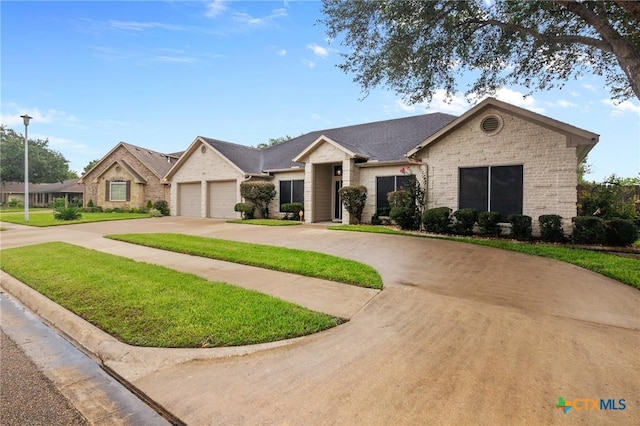 204 Crosswind Dr, Victoria, TX 77904 - single story home featuring curved driveway, an attached garage, a front lawn, brick siding, and stone siding