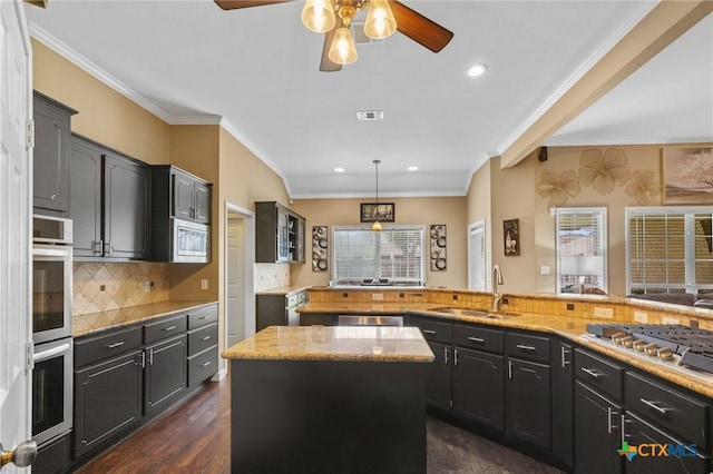 204 Crosswind Dr, Victoria, TX 77904 - kitchen featuring appliances with stainless steel finishes, a ceiling fan, a kitchen island, dark wood-style flooring, and backsplash