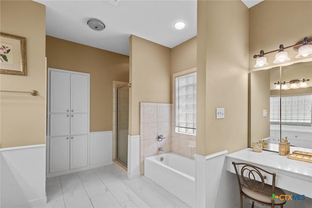 204 Crosswind Dr, Victoria, TX 77904 - bathroom featuring a bath, healthy amount of natural light, a stall shower, marble look tile flooring, and a wainscoted wall