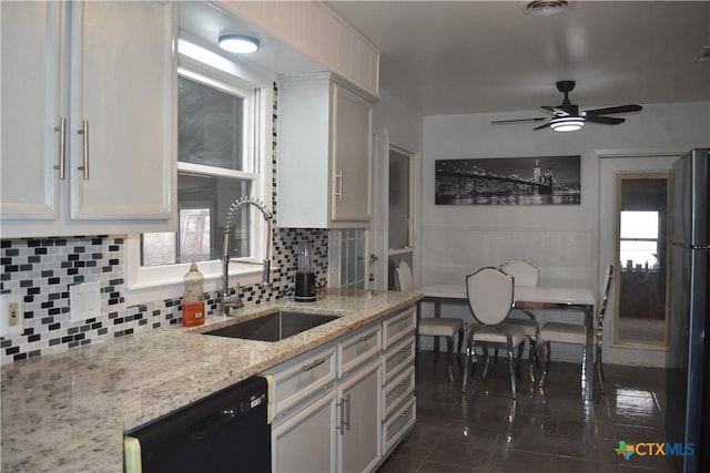 kitchen featuring tasteful backsplash, sink, white cabinets, light stone counters, and black appliances