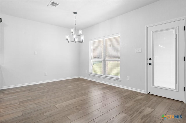 unfurnished dining area featuring a chandelier and light hardwood / wood-style flooring