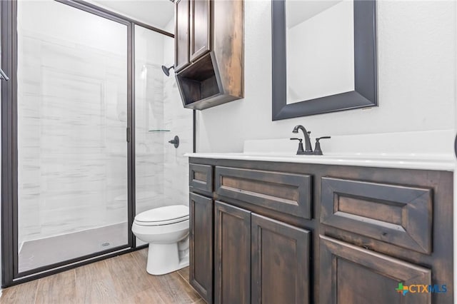 bathroom with hardwood / wood-style floors, vanity, toilet, and walk in shower